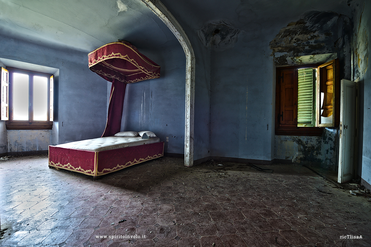 Foto di un letto a baldacchino rosso dentro una Villa abbandonata